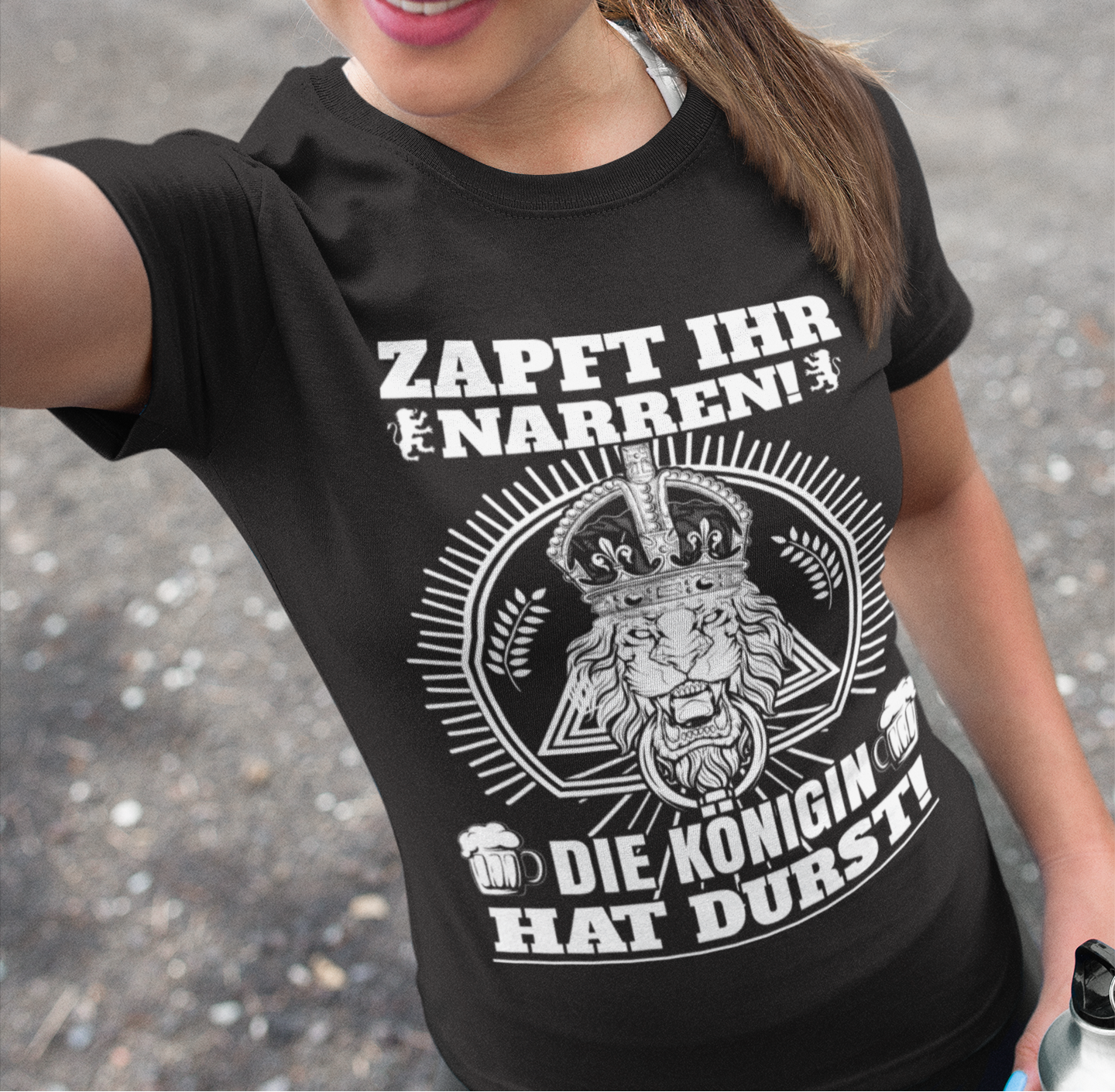 Eine Frau trägt das Königin hat Durst Shirt draußen und macht ein Selfie