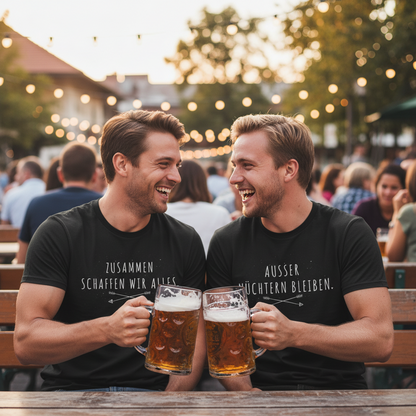Zwei Männer im bayerischen Biergarten tragen schwarze Partnerlook T-Shirts mit "Zusammen schaffen wir alles" und "Außer nüchtern bleiben", stoßen lachend mit Bierkrügen an, warme Lichterketten-Atmosphäre