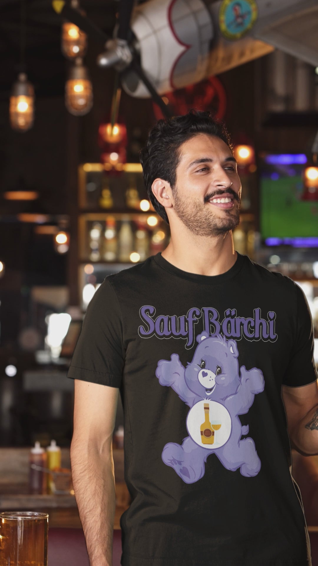 Mann mit Sauf Bärchi Glücksbärchi T-Shirt wird in einer Bar gefilmt und ist glücklich