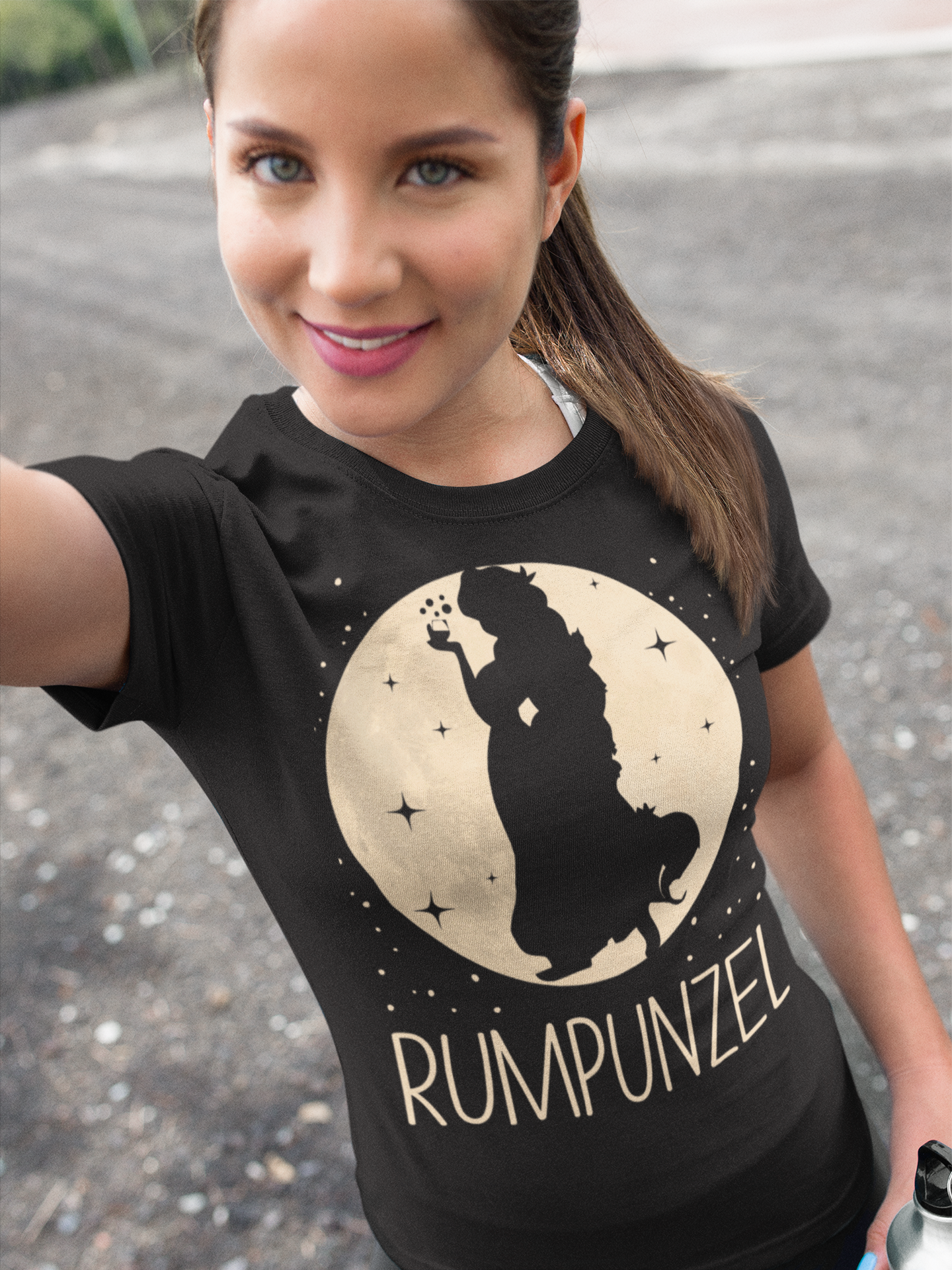 Eine Frau trägt ein RUMPUNZEL Shirt im Freien und macht ein fröhliches Selfie