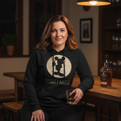 Eine Frau trägt den Whiskey Mouse Hoodie entspannt an der Home Bar mit Whiskeyflasche auf dem Tisch